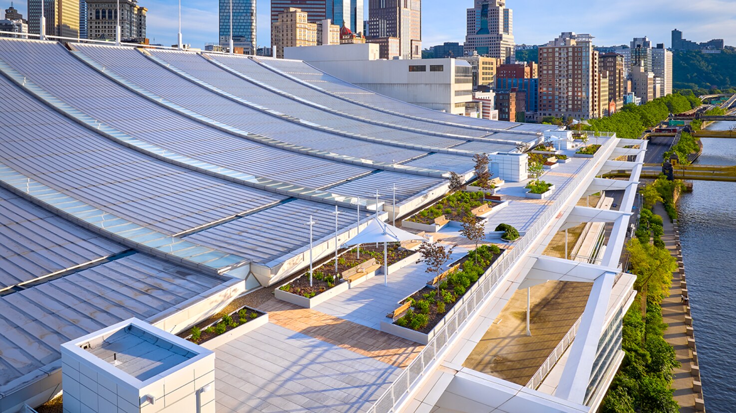Rooftop terrace and landscaped garden deck overlooking a river and downtown city skyline on a sunny day.