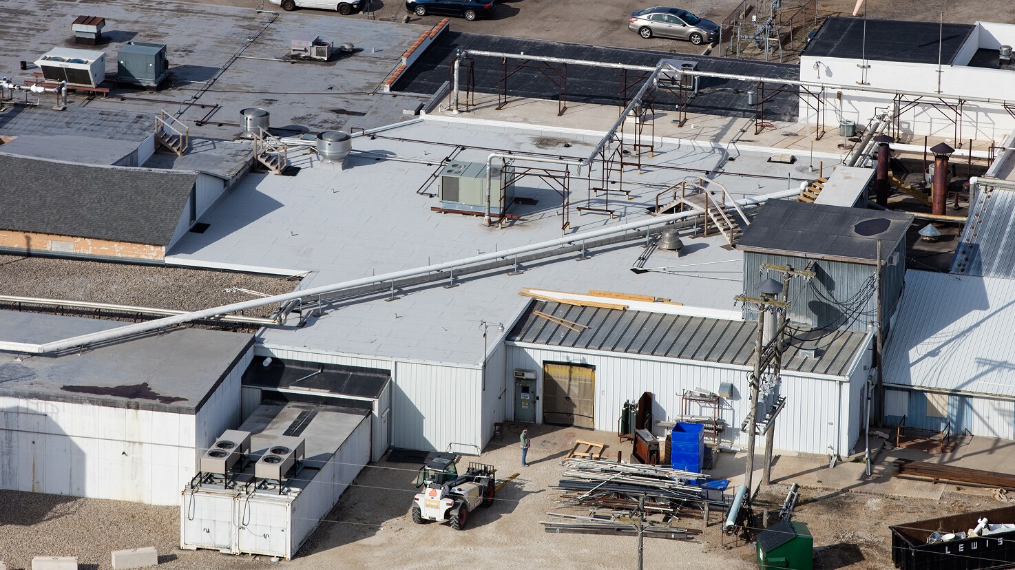 Aerial view of the Maple Leaf Farms industrial facility in Indiana, showing multiple contiguous roofs, extensive rooftop piping, and adjacent parking.