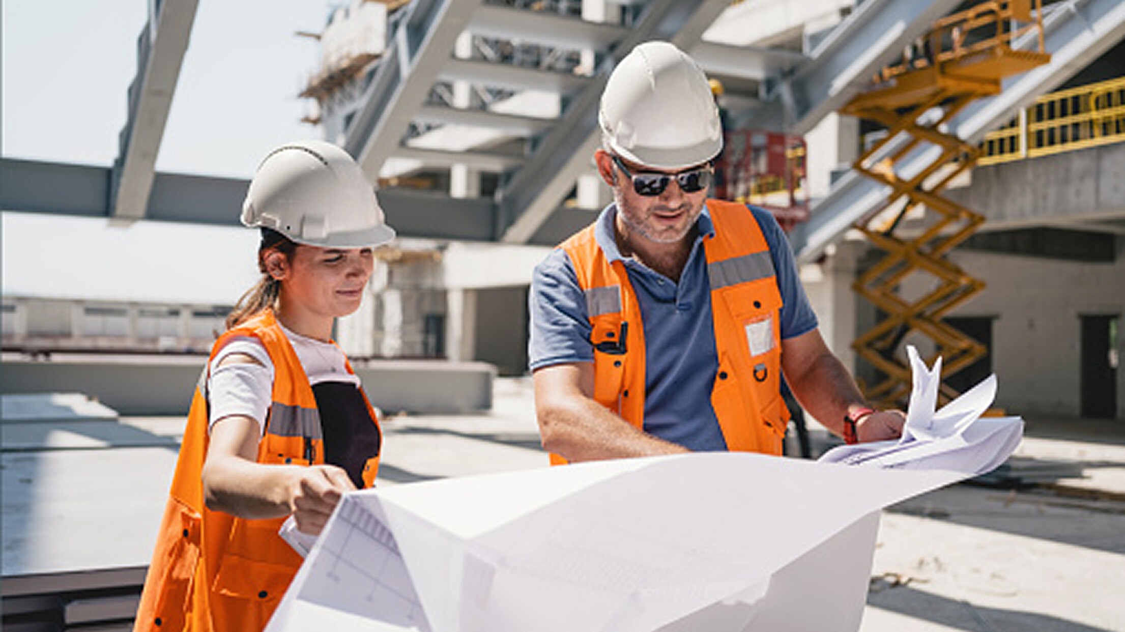 Two building professionals examining blueprints at a job site.