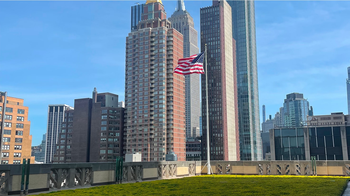 Urban green space on a rooftop with views of the city skyline and the American Flag